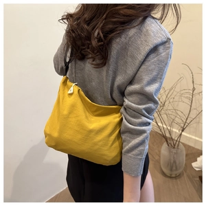 Detail view of mustard yellow waterproof nylon bag with stylish triangle zipper pull