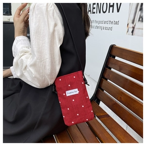 Detail of red floral cotton shoulder bag with Creative Cat label worn by a model