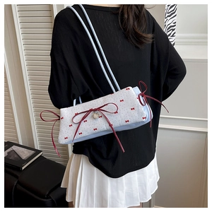 Détail du sac à nœud bleu clair avec breloque cœur et rubans rouges sur un modèle