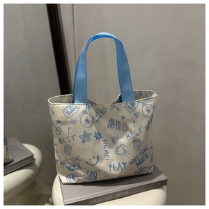 Détail d'un sac cabas en toile blanche avec graffitis bleus et anses en nylon