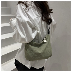 Green nylon shoulder bag with natural texture shown from a side back view on a model