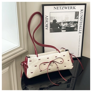 Détail du sac bandoulière en tissu crème avec motif nœud rouge et nœud en cuir élégant
