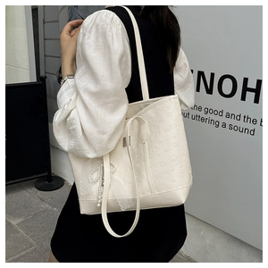 Gros plan du sac cabas blanc gaufré avec un pendentif élégant en dentelle et perles