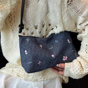 Blue denim crossbody bag with floral patterns and Creative Cat text on a model