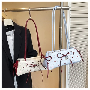 Détail des sacs baguette crème et bleu avec imprimés nœuds rouges et breloque en cœur