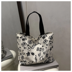 Détail du sac cabas en toile avec imprimés graffiti et bandoulières noires solides