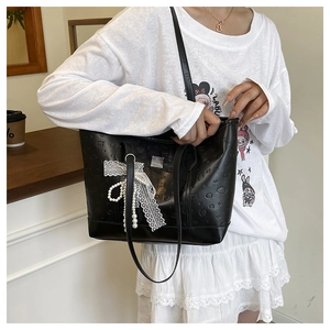 Détail du sac cabas noir avec motifs Labubu gaufrés et accessoire de nœud en dentelle