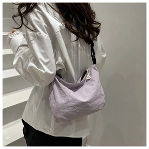 Detail of light purple nylon shoulder bag with black strap on a minimalist staircase