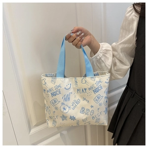 Détail des imprimés graffiti bleus sur le sac fourre-tout en toile blanc crème