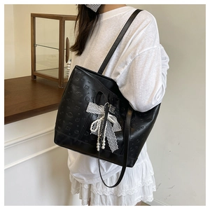 Détail du sac cabas noir avec motifs de cœurs gaufrés et nœud en dentelle à perle