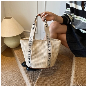 Gros plan détaillé du sac en paille tissée avec broderie SUMMER & BEAUTY sur la bandoulière