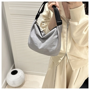 Detail of grey nylon crescent bag with adjustable strap on a casual model outfit