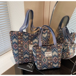 Detail of two ethnic geometric jacquard tote bags with purple handles on a wooden table