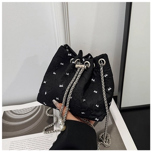Detail of black drawstring bucket bag with white bows, silver chain and pearl accent