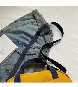 Close-up of yellow nylon crossbody bag with smooth adjustable long navy blue strap