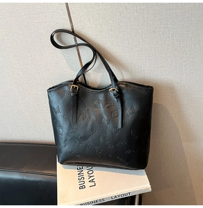 Detail view of black PU leather tote bag with embossed butterfly and umbrella patterns