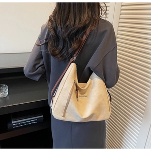 Detail of off-white shoulder bag featuring fashion logo and brown leather strap