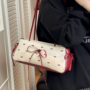 Sac à bandoulière crème chic à pois rouges avec nœud et pendentif cœur sur un modèle