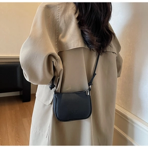 Litchi pattern mini crossbody bag shown on a model with a beige coat in a home setting