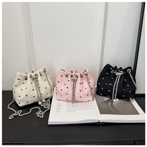 Detailed view of quilted bucket bags with black bow patterns and pearl drawstring charms