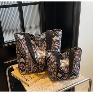 Set of two bohemian woven tote bags with geometric patterns on marble surface