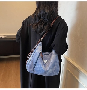 Detail view of large blue canvas hobo bag with brown strap and metal triangle decor