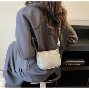 Silver litchi texture crossbody bag worn by a model in a minimalist lifestyle setting
