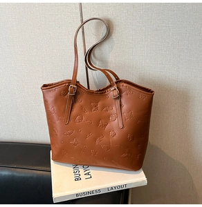 Detailed view of brown PU leather tote bag with embossed puppy and floral patterns