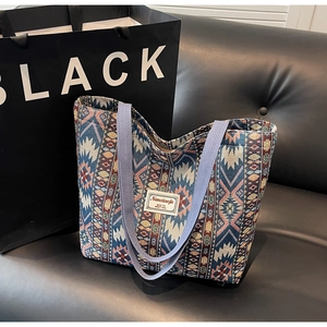 Detail of colorful geometric woven tote bag featuring wide purple straps and textile texture