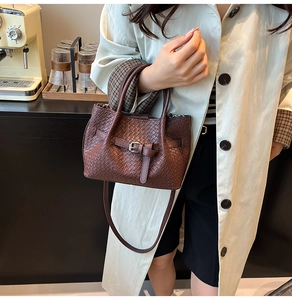 Détail d'un sac seau en cuir tressé marron avec décoration de sangle à boucle