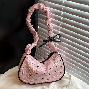 Pink ballet-style shoulder bag with black bow patterns and ruffled shoulder strap