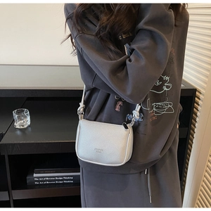 Model view of a silver lychee pattern crossbody bag with a delicate shoulder strap