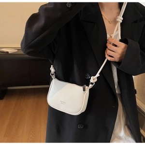 Close-up of white crossbody bag with lychee texture and thick rope knot strap detail