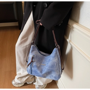 Detail of blue denim tote bag with brown straps and metal FASHION logo on front
