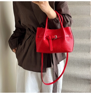 Détail de la texture tressée rouge et de la boucle de ceinture sur ce sac à main chic