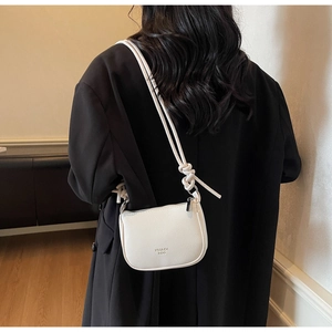 Close-up of white lychee pattern crossbody bag with knot shoulder strap and logo detail