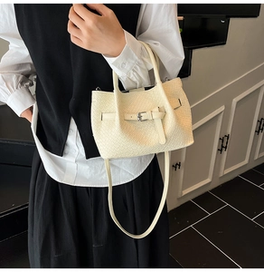 Détail du sac seau blanc tressé montrant la texture croisée et la boucle métallique