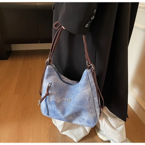 Detailed side view of washed blue tote bag with FASHION metal logo and side zipper
