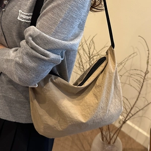 Beige crescent crossbody bag with pleated nylon fabric and adjustable black strap