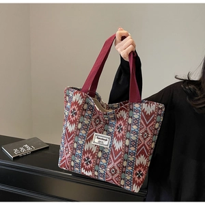 Detailed shot of ethnic jacquard tote bag with geometric patterns and red canvas handles