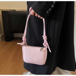 Detailed macro view of pink lychee textured leather mini crossbody bag with knot strap