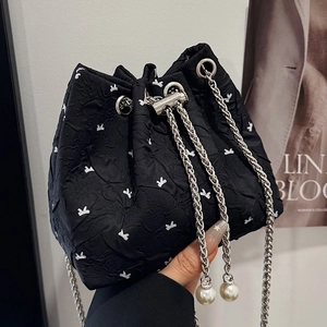 Fashionable black pleated bucket bag with white bow print and pearl drawstring details