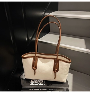 Detail of cream tote bag with brown knotted handles and Fashion & Bags text on books