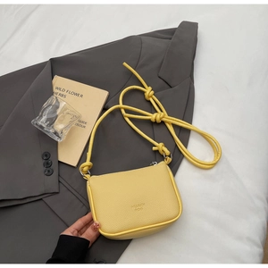 Detail of yellow lychee texture mini crossbody bag with knotted strap on suit