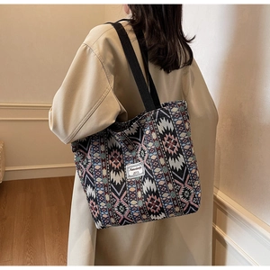Rear view of a woven ethnic tote bag with colorful geometric patterns and black straps
