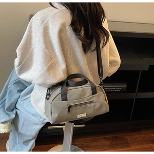 Model wearing a grey nylon Boston crossbody bag with top handles and adjustable strap