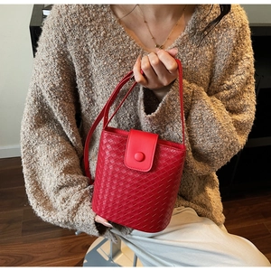 Close-up of red woven bucket bag featuring detailed leather craftsmanship on a brown sweater