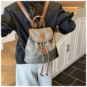 Vue détaillée d'un sac à dos vintage en toile grise et cuir porté par un mannequin