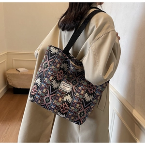 Detail of bohemian tote bag showing geometric patterns on a casual beige trench coat