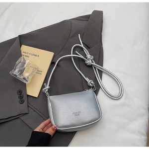 Detail of silver litchi grain crossbody bag showing branded texture and knotted strap